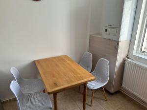 un tavolo in legno con 4 sedie e un frigorifero di Apartament Amalia a Roman