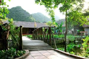 a wooden bridge over a pond in a garden at Whisper Nature Bungalow & Resort in Cat Ba