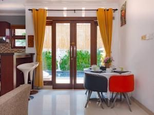 a dining room with a table and yellow curtains at Villa Ariani Keselurahan, 3 BR in Keramas