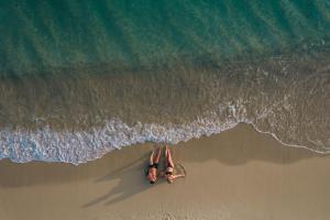 布拉卡的住宿－Aegean Palace，两人躺在海滩上的冲浪板上