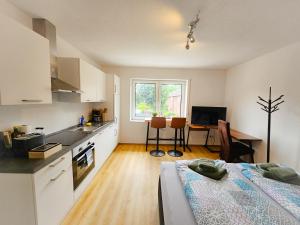 a kitchen with white cabinets and a table with a bed at EcoCube 441 - 1Wohnküche, Backofen, TV, Parkplatz in Meppen