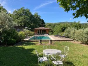 a table and chairs in the grass next to a pool at Château de Peyrolles in Apt