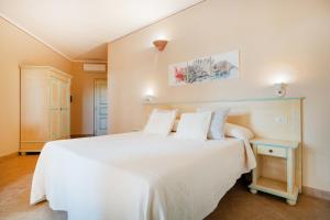 a bedroom with a large white bed with white sheets at Hotel Lu Pitrali in San Teodoro
