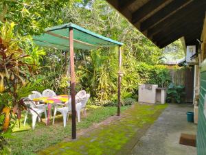 un patio con mesa, sillas y sombrilla en St Lucia Wilds en St Lucia