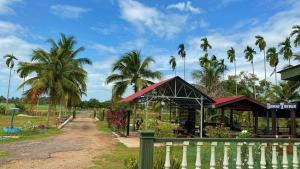 a building with palm trees behind a fence at Dangau Tokwan in Pokok Sena