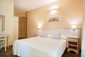 a bedroom with a white bed with two blue pillows at Hotel Lu Pitrali in San Teodoro