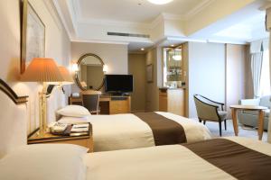 a hotel room with two beds and a mirror at Imabari Kokusai Hotel in Imabari