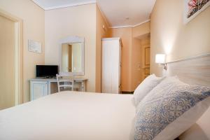 a bedroom with a large white bed and a desk at Hotel Lu Pitrali in San Teodoro