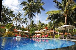 una piscina con sillas, sombrillas y palmeras en Teluk Karang Dive & Spa Resort, en Tejakula