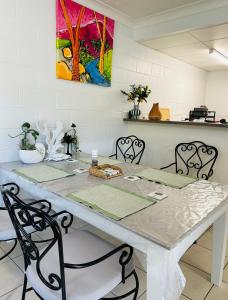 einen Esstisch mit Stühlen und ein Gemälde an der Wand in der Unterkunft Holiday at Henry St West End, Townsville QLD 3 night min in North Ward