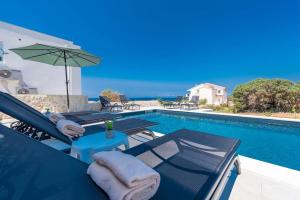 einen Pool mit Stühlen, einem Sonnenschirm und einem Tisch in der Unterkunft Sunset mood modern ap with a pool for 6 in Novalja