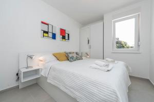 ein weißes Schlafzimmer mit einem weißen Bett und einem Fenster in der Unterkunft Sunset mood modern ap with a pool for 6 in Novalja + 50 Fotos