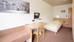 Kleines Zimmer mit einem Schreibtisch und einem Bett. in der Unterkunft Hotel Victoria in Weil am Rhein