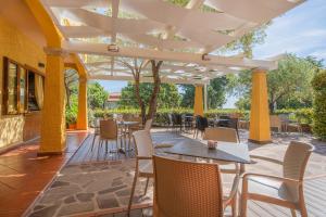 un patio avec des tables et des chaises sous une pergola dans l'établissement Hotel Lu Pitrali, à San Teodoro
