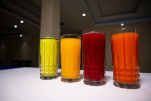 four different colored glasses sitting on a table at Armaflex Hotel Lira in Lira