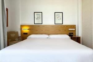 a bedroom with a large white bed with three pictures on the wall at Hotel Don Ignacio in San José