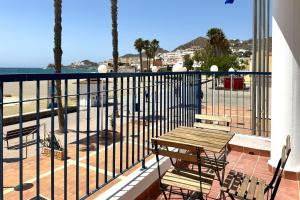a balcony with a wooden table and chairs and the ocean at Hotel Don Ignacio in San José