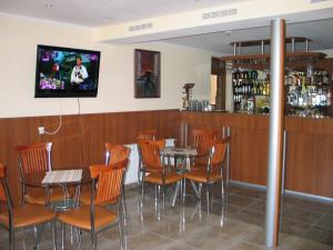 a bar with tables and chairs and a tv on the wall at Kovanlika Hotel in Razgrad