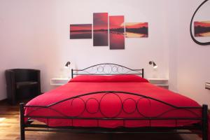 a red bed in a bedroom with paintings on the wall at Visit Cagliari in Cagliari