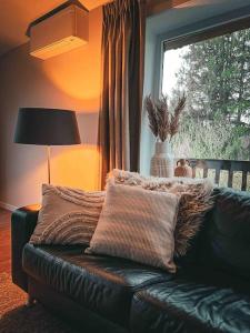 a living room with a leather couch and a window at Chalet Wijd Weg in Rendeux
