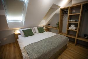 a bedroom with a bed with white sheets and green pillows at Hiša TRELC- sobe in Komenda