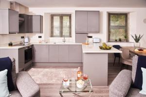 a kitchen and living room with white cabinets and a table at Harbour Breeze - On Torquay's iconic marina with hot tub in Torquay
