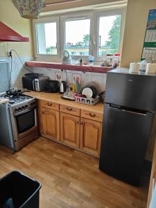 Una cocina con refrigerador negro y gabinetes de madera. en Całe mieszkanie 2 pokojowe na wyłączność centrum Częstochowy, bardzo blisko Jasnej Góry, 2 duże łóżka, en Częstochowa