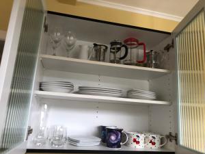 a cupboard with plates and wine glasses and dishes at Close To Nature & City in Wellington +8 photos
