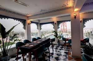 a dining room with a table and chairs and windows at Hotel Darbargarh, Udaipur in Udaipur