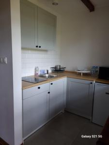 a kitchen with white cabinets and a sink at Domek letniskowy w Karwiku in Karwik +3 photos