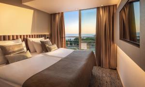 a hotel room with a bed and a large window at Aminess Vival Maestral Hotel in Novigrad Istria