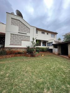 a white house with a yard in front of it at 1 bedroom cottage Westlands central location -by Zuri homes in Nairobi