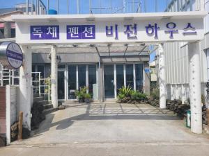 una entrada a un edificio con un cartel en él en Jeju Vision House en Jeju