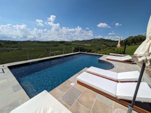 a swimming pool with two chairs and an umbrella at Tenuta Le More in Calosso +22 photos