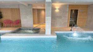 a large swimming pool with a fountain in a building at Hotel Collingwood BW Signature Collection in Bournemouth