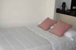 a white bed with two pink pillows on it at Estudio centrico de lujo in Vigo