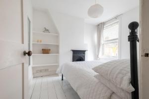 een witte slaapkamer met een bed en een open haard bij Charming Kings road in Bury Saint Edmunds