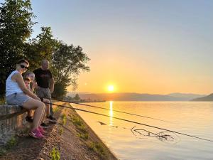 a group of people sitting on a bench watching the sunset at Apartman Velojić in Donji Milanovac