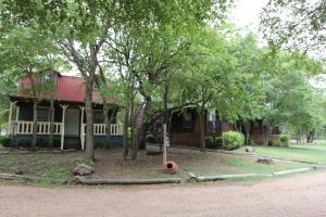 a house with a red roof and trees in front of it at Almond Cabin in Fredericksburg