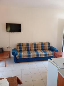 a blue couch sitting in a living room with a tv at Apartments Gregory & George in Hanioti