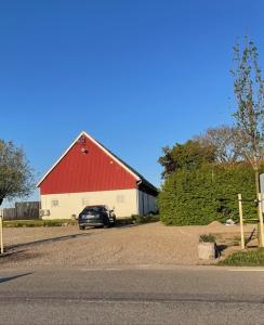 ein Auto, das vor einer roten und weißen Scheune parkt in der Unterkunft Glivarpagården in Hammenhög