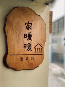 ein hölzernes Schild an der Wand, auf dem steht: in der Unterkunft 家暖暖,老屋新生,房源內有戶外空間,嘉義市民宿013號 in Chiayi