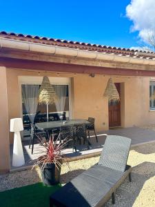 um pátio com uma mesa e cadeiras e uma casa em Maison piscine & spa Vallon Pont d'Arc em Vallon-Pont-dʼArc