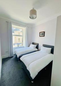 two beds in a room with a window at Beautiful spacious apartment in town centre in Oban