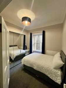 a bedroom with two beds and a window at Beautiful spacious apartment in town centre in Oban