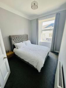 a bedroom with a white bed and a window at Beautiful spacious apartment in town centre in Oban