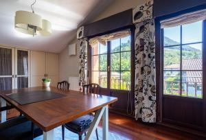 a dining room with a wooden table and windows at Urdaibai Boutique in Altamira