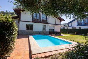 a villa with a swimming pool in front of a house at URDAIBAI Boutique in Altamira