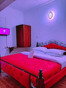 1 dormitorio con 1 cama grande de color rojo y reloj en la pared en Js Hotel & Accommodation, en Nakuru