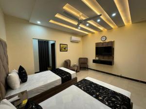 een hotelkamer met 2 bedden en een televisie bij Gold Pine Hotel Lahore in Lahore